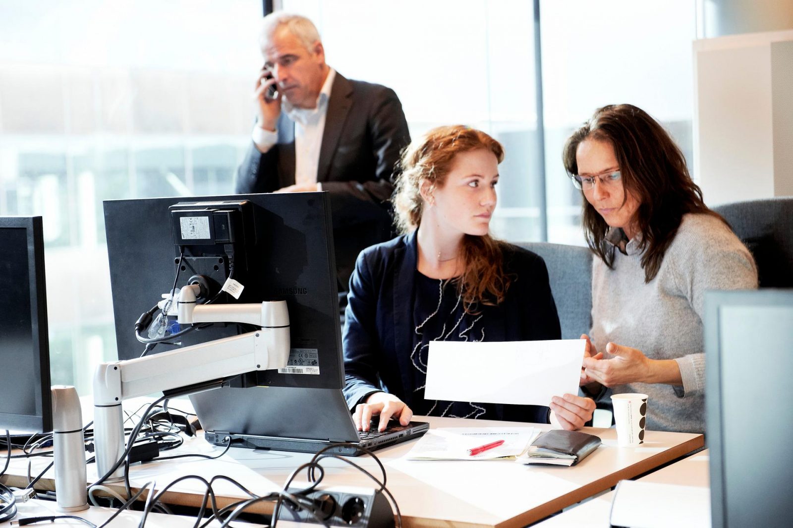 2 vrouwen in overleg, telefonerende man