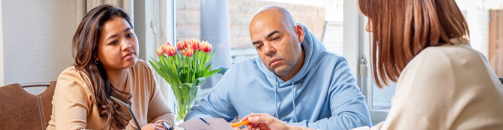 Mevrouw geeft een echtpaar toelichting en wijst op een brief.