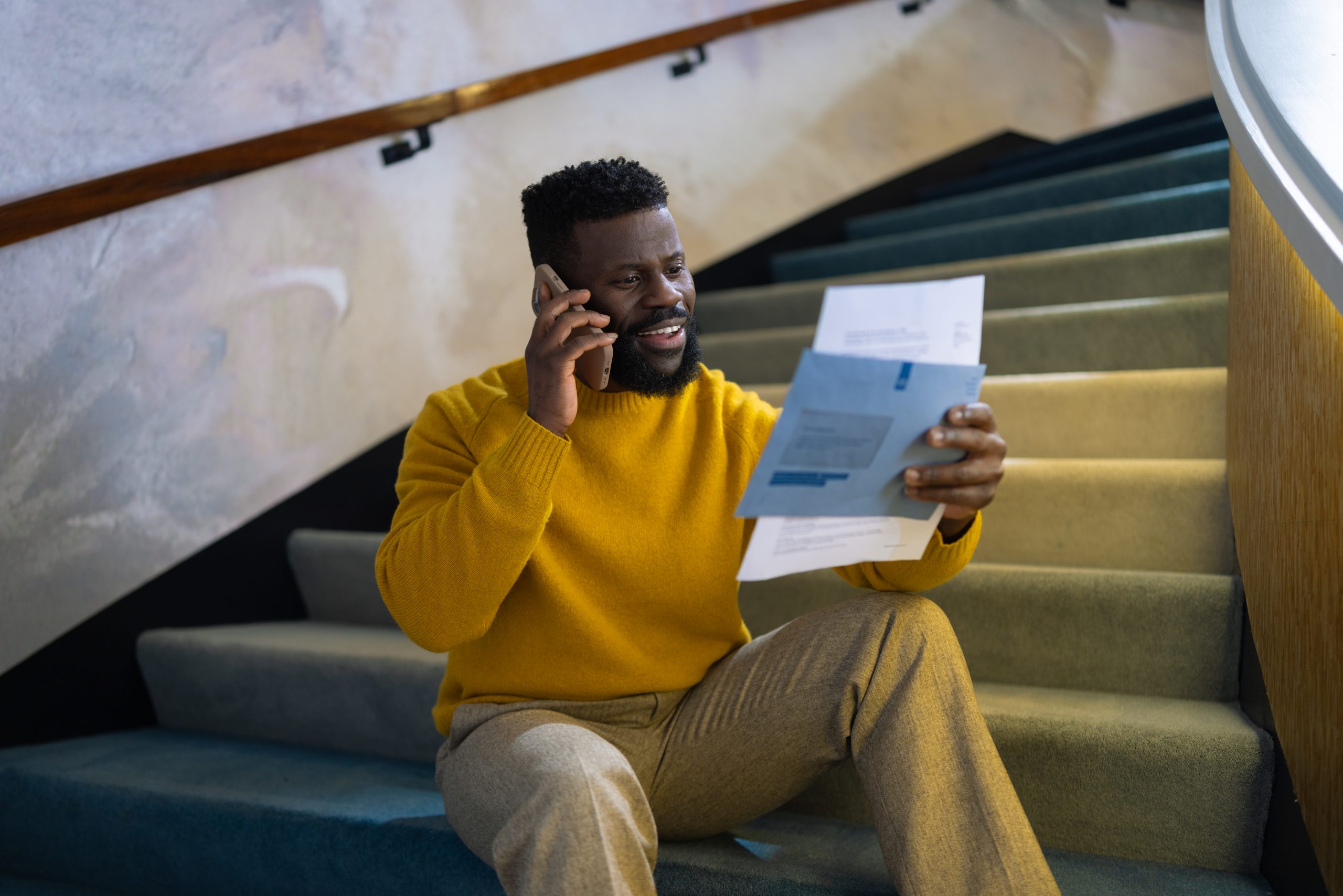 Persoon die op de trap belt met de BelastingTelefoon en een blauwe envelop en brief van de Belastingdienst in zijn handen heeft.